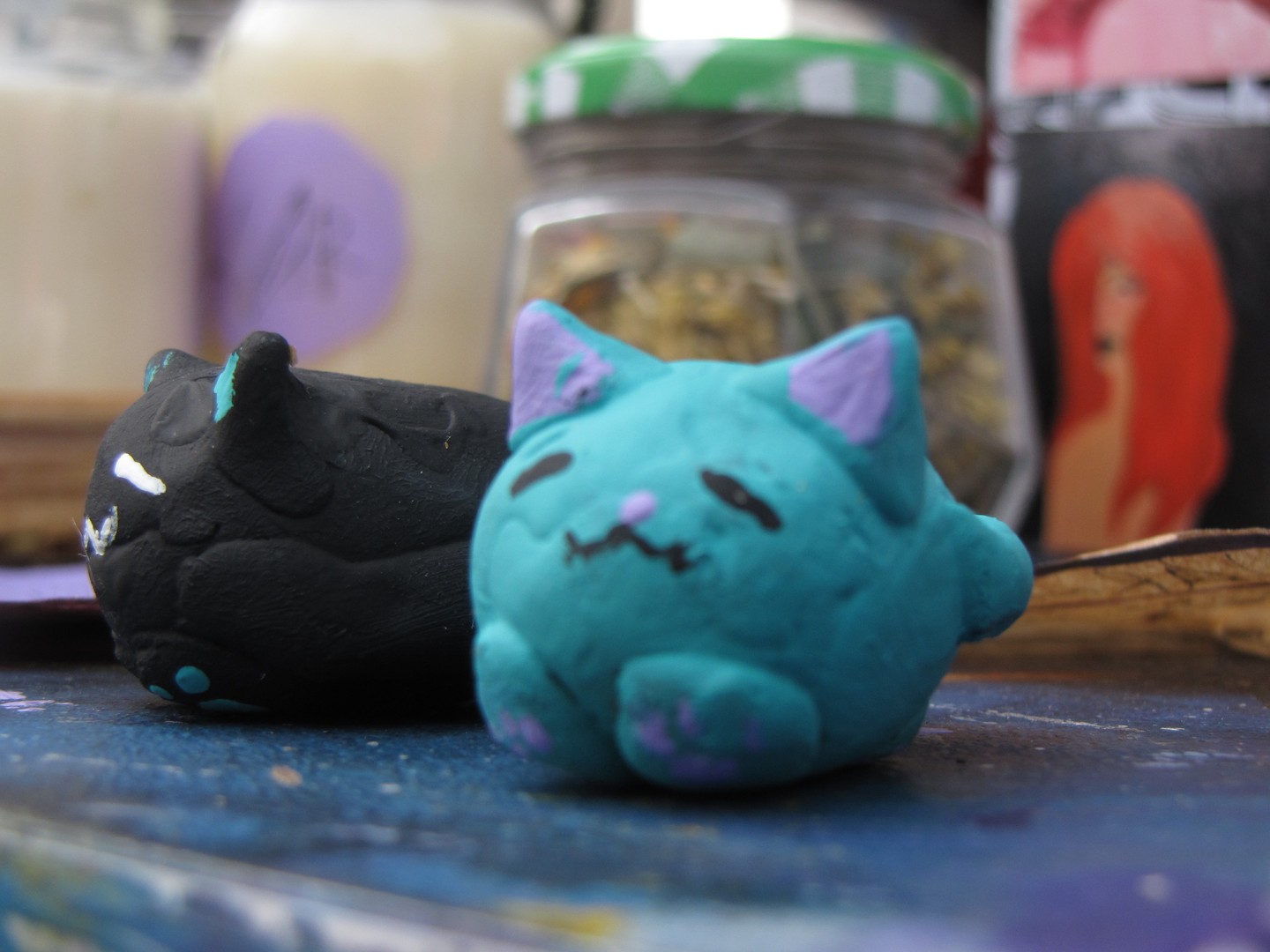 Close-up photograph of two small handmade cat figurines, likely sculpted from clay, polymer clay, or a similar modeling material.